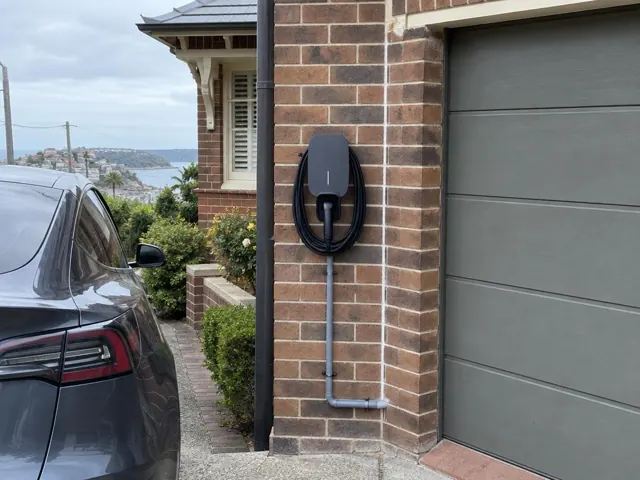 Wall-mounted EV charger on a brick garage wall beside a driveway in Dover Heights