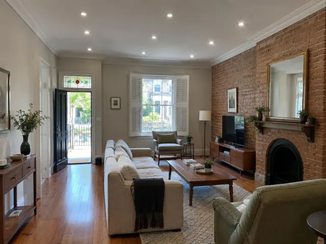 Living room with recessed downlights, brick fireplace and timber floors in Woollahra
